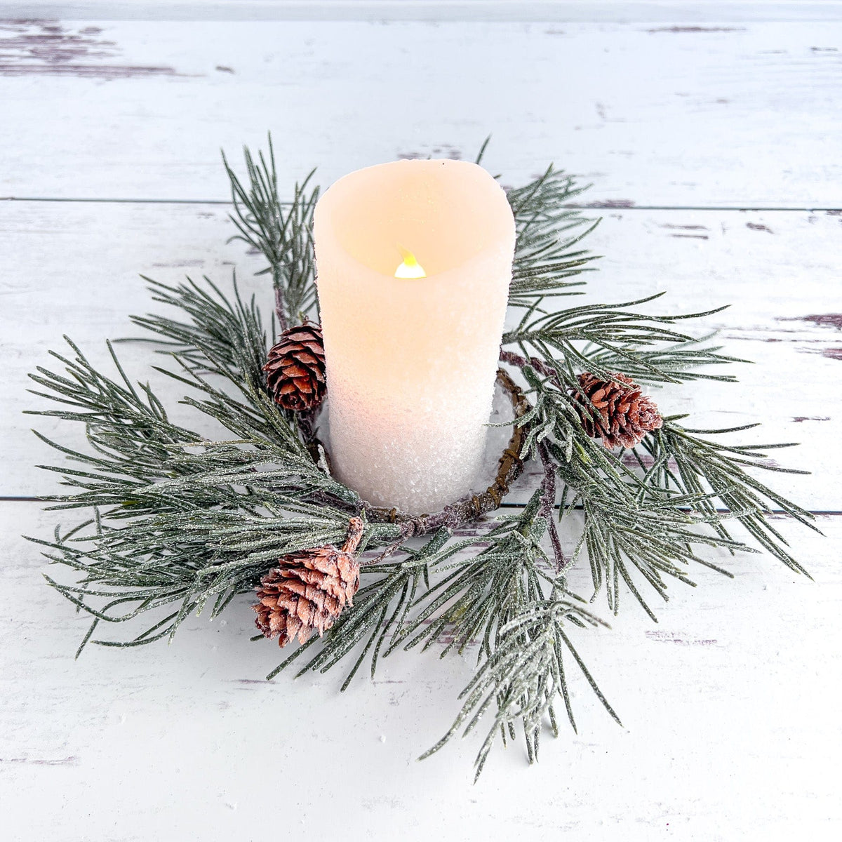 a lit candle surrounded by pine cones and evergreen needles